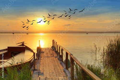 Plakat zachód słońca na tradycyjnej drewnianej łodzi