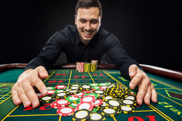 Young handsome man playing roulette wins at the casino