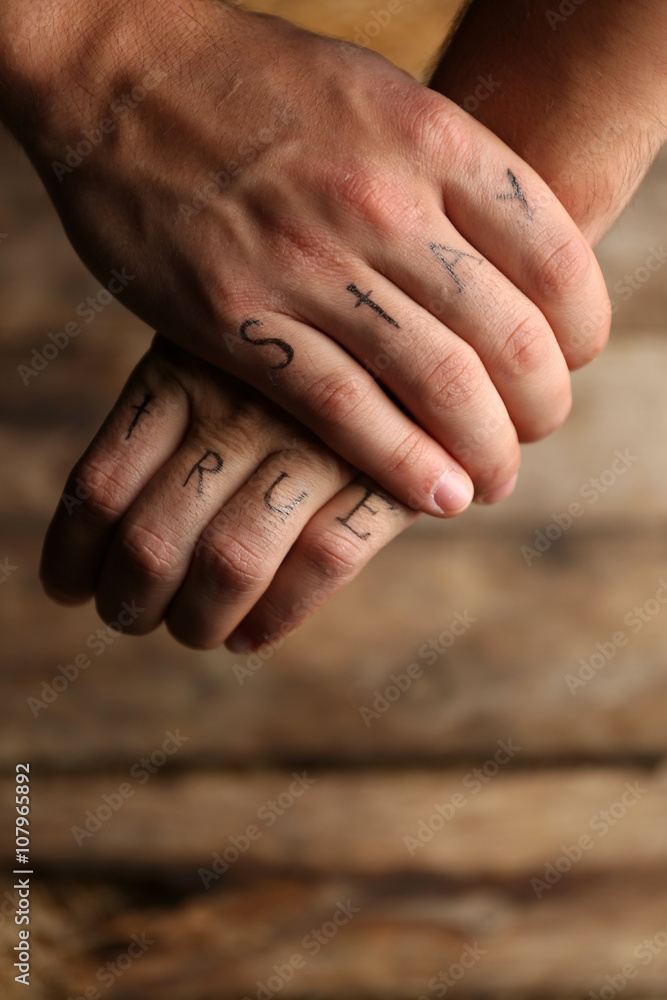 Tattoo inscriptions on male fingers drawn with marker