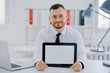 © kuprevich - Businessman holding tablet in hands in office