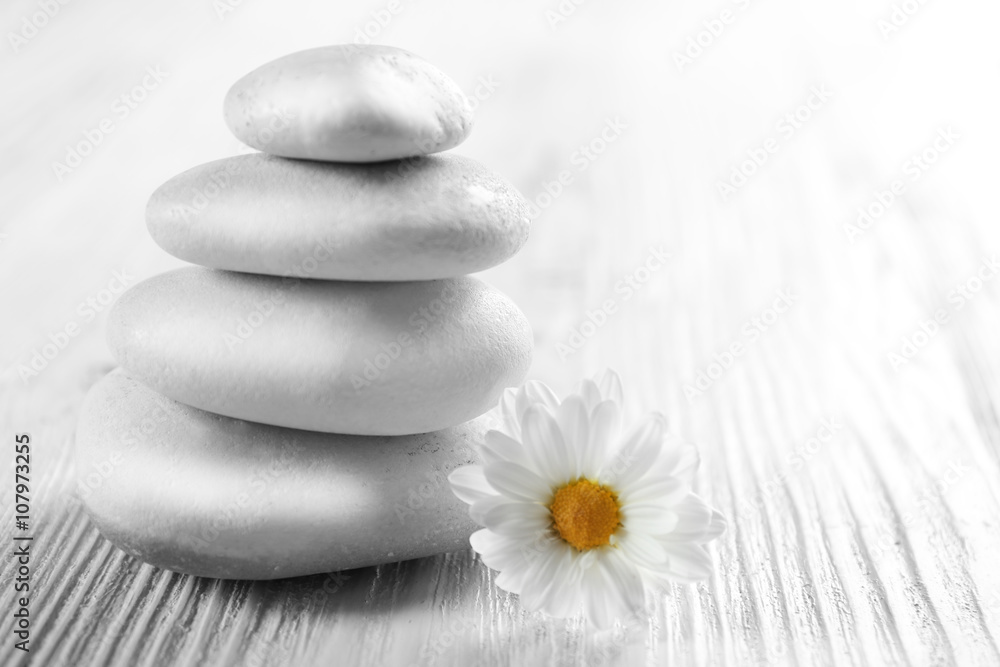 Spa stones with beautiful flower on white wooden table