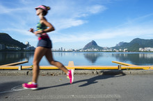 A Jogger Running Past In Motion Blur A Calm Morning View Of Lagao Rodrigo De Freitas Lagoon, A Popular Recreation Destination In Rio De Janeiro, Brazil