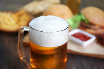 Wall Mural - Glass mug of light beer with snacks on dark wooden table, close up