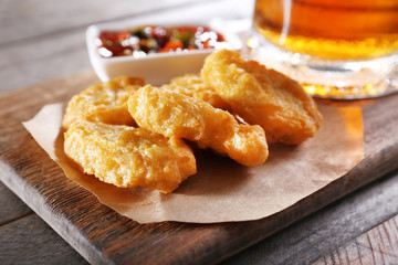 Wall Mural - Glass mug of light beer with snacks on wooden table, close up