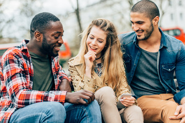 Group of friends two men and one woman with mobile, sitting on a