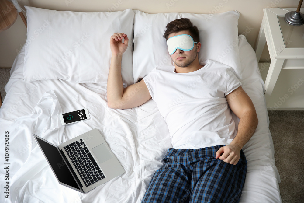 Young man sleeping with blindfold in bed at home