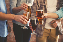 Male Group Clinking Glasses Of Dark And Light Beer On Brick Wall Background