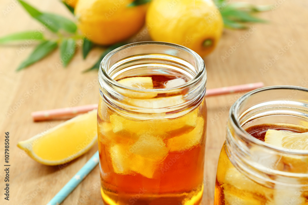 Jar of ice lemon tea with straw on wooden table