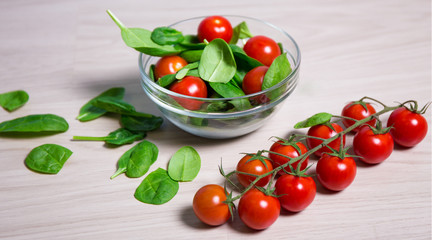 Wall Mural - healthy food concept - spinach and tomatoes on wooden table