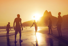 Silhouette Of Locals Playing Ball At Sunset In Ipanema Beach, Rio De Janeiro, Brazil. 