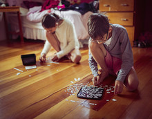Mixed Race Children Doing Puzzles On Bedroom Floor