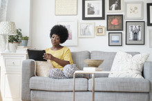 African American Woman Using Digital Tablet On Sofa