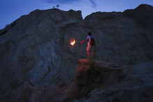 Caucasian Man Holding Torch Under Rocky Cliff