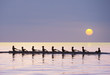 © Pete Saloutos/Blend Images - Silhouette of rowing team practicing on still lake
