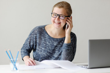 Smiling business woman sitting at office Desk and working with l