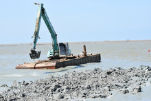 Green Excavator With A Shovel Standing On The Floating Sea A Sea Of Mud.