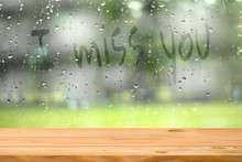 Empty Wooden Table Near Water Drop On Window With Wording I Miss You Blurred Garden Background. Ready For Product Display Montage. Love And Lonely Concept.