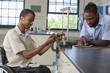 © Disability Images/Blend Images - Paraplegic student and classmate working in science classroom