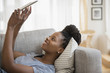 © JGI/Jamie Grill/Blend Images - Woman using digital tablet on sofa