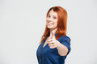 © Drobot Dean - Cheerful attractive redhead young woman showing thumbs up