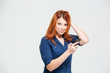 © Drobot Dean - Smiling pretty redhead young woman using smartphone