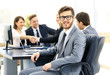 © ASDF - Portrait of mature business man smiling during meeting with colleagues in background