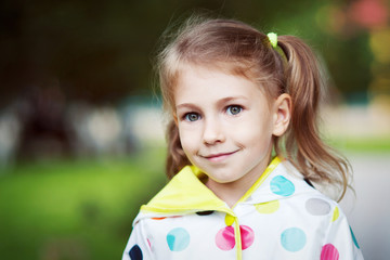 A large portrait of a girl with two ponytails on her head, coat in peas.