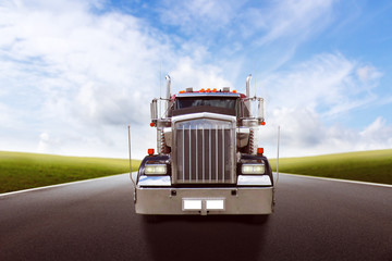 Truck driving on country road against blue sky