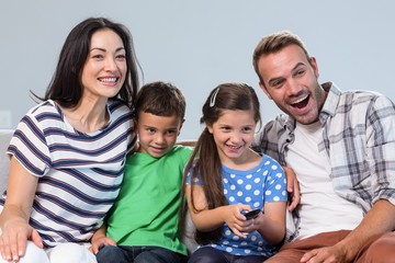 Wall Mural - Happy family watching television with their two children