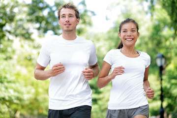 Fitness healthy lifestyle. Happy couple running summer training for marathon in Central Park Manhattan, New York. Asian female model and Caucasian sport fitness male athlete enjoying jogging together.