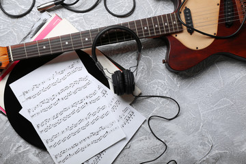 Electric guitar and headphones with music notes on grey background