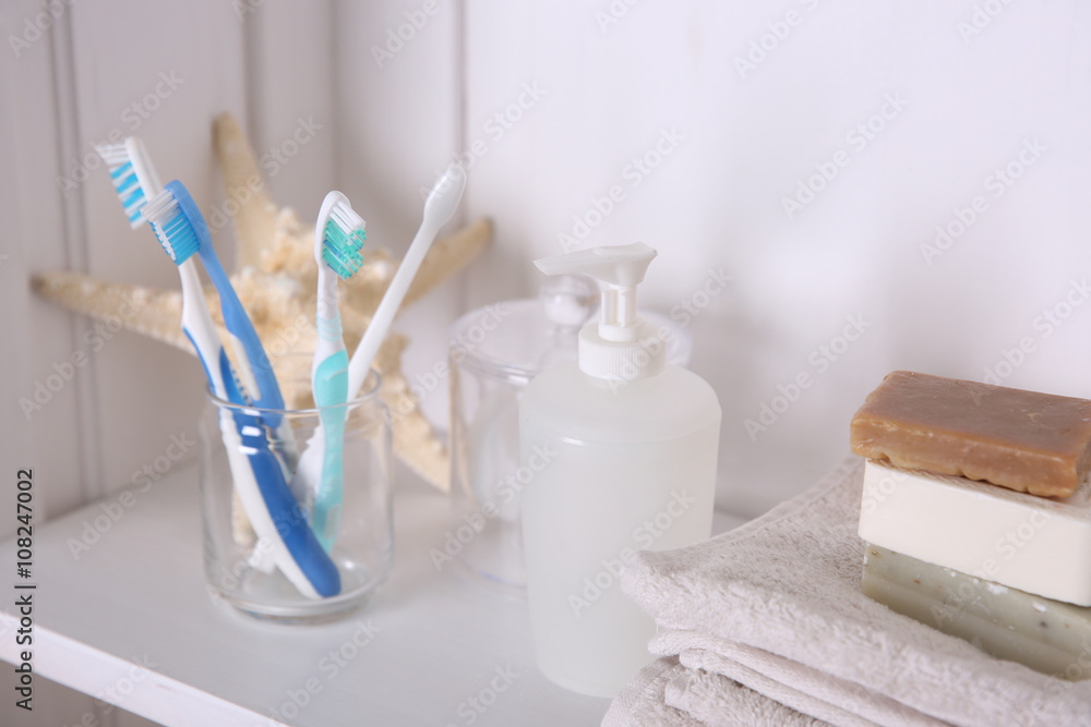 Bathroom set with towels, dispenser, toothbrushes and soap on a light shelf