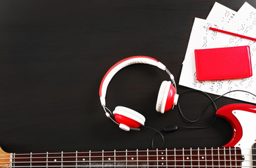 Wall Mural - Electric guitar with headphones and notes on black wooden background