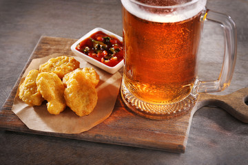 Wall Mural - Glass mug of light beer with snacks on wooden table, close up