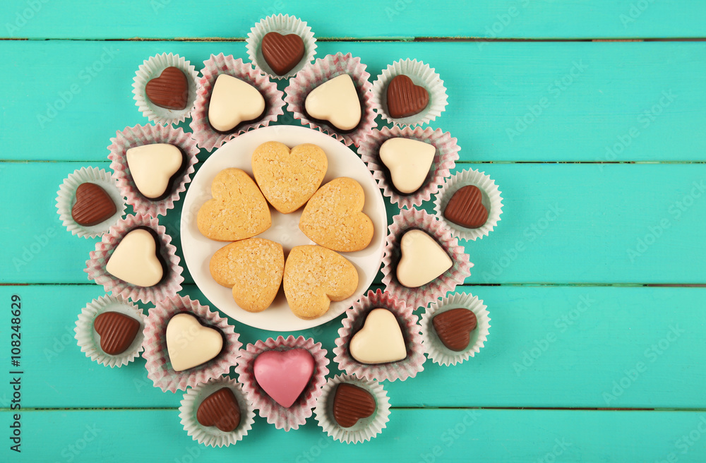 Valentine's Day concept. Composition of delicious chocolate candies and tasty cookies on turquoise wooden background