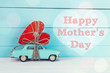 Mothers day background with miniature blue toy car carrying a he