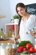 © lenets_tan - Young woman standing by the stove in the kitchen