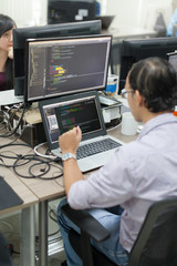 Wall Mural - asian outsource software developer looking screen sitting at desk