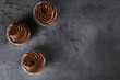 Three chocolate cupcakes on grey background