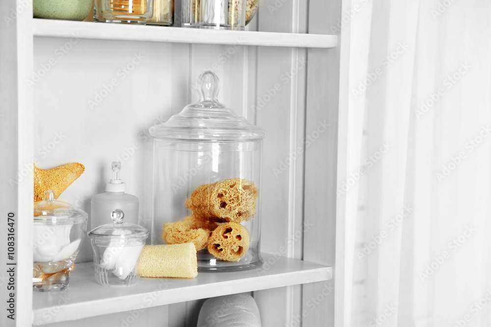 Bathroom set with sponges and dispenser on a shelf in light interior