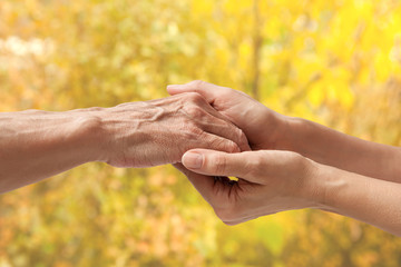 Wall Mural - Hands of an elderly senior holding the hand of a woman