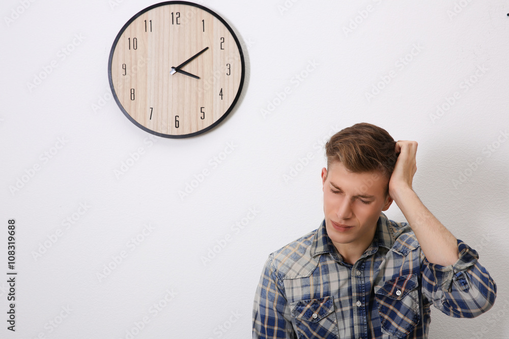 Young handsome man and clock on wall