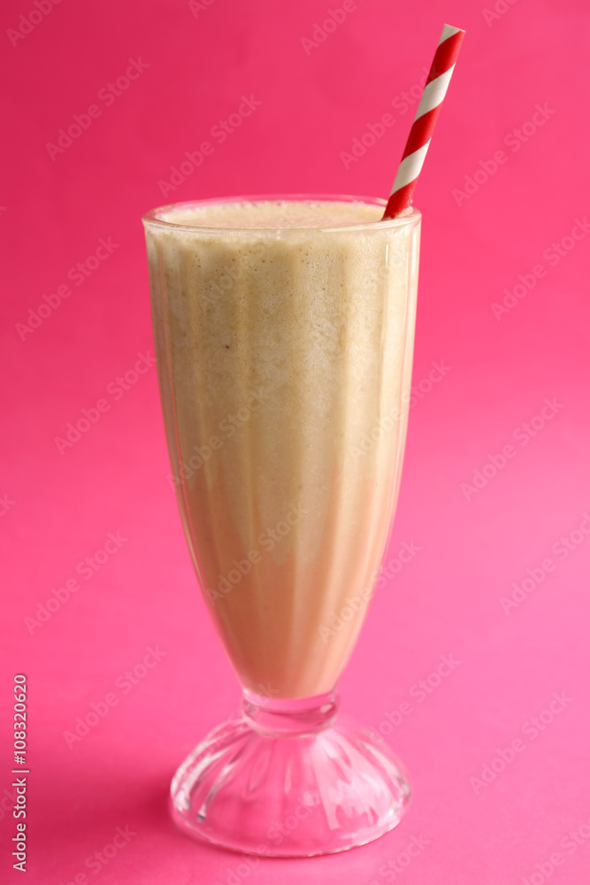 Glass of milk cocktail on pink background