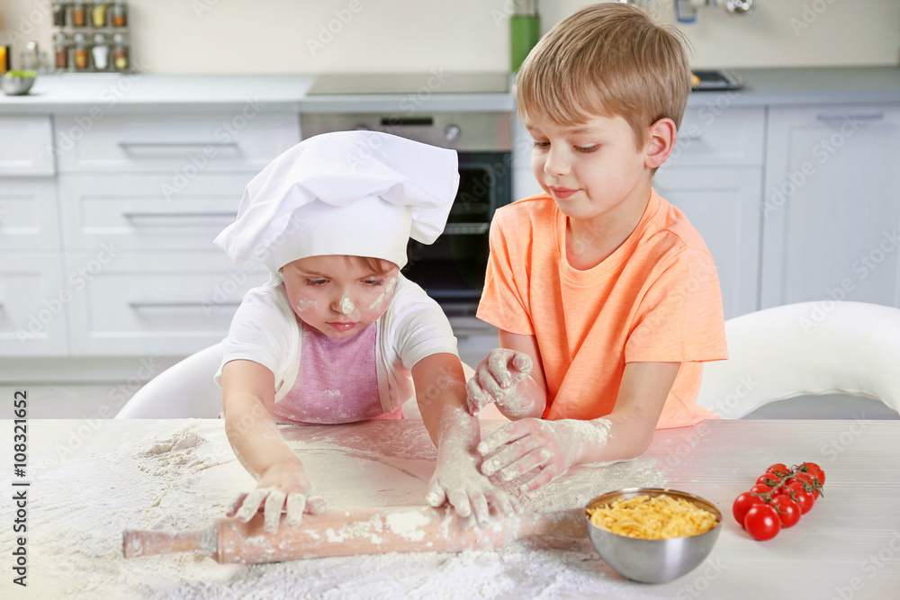 Two little boys rolling out a pizza dough, close up