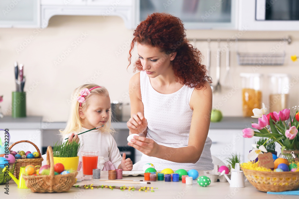 Mother and daughter decorating Easter eggs in the kitchen