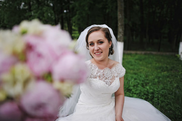 Wall Mural - Beautiful bride showing peonies wedding bouquet in hand