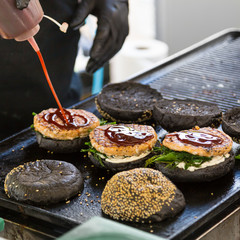 Wall Mural - Chef making beef burgers outdoor on open kitchen international food festival event. Street food ready to serve on a food stall.