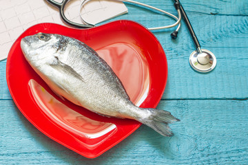 Wall Mural - Fish on red heart plate and stethoscope cardiology diet concept
