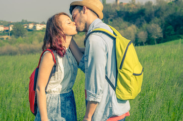 Couple of students lovers kissing at the park holding their backpacks