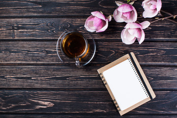 Wall Mural - Cup of black tea and flower magnolia on wooden boards.